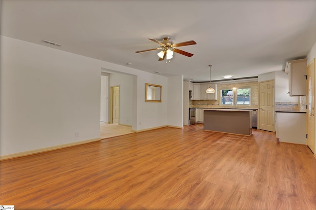 unfurnished living room featuring ceiling fan, light wood-type flooring, and baseboards