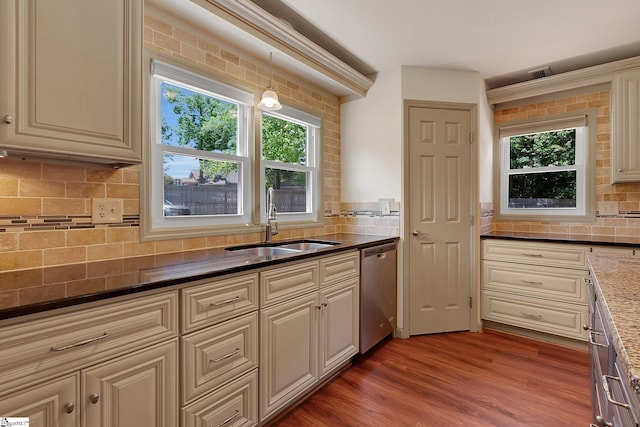 kitchen featuring stainless steel dishwasher, a sink, tasteful backsplash, and plenty of natural light