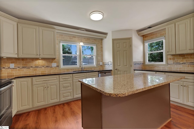 kitchen with a sink, cream cabinetry, stainless steel appliances, and backsplash