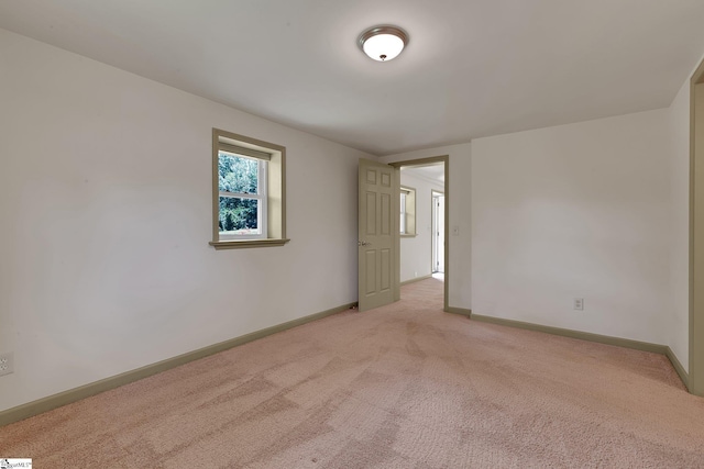 unfurnished room with light colored carpet and baseboards