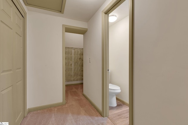 hallway featuring baseboards and light carpet