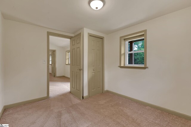 unfurnished room featuring light colored carpet and baseboards