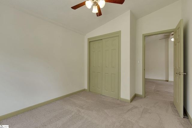 unfurnished bedroom with light colored carpet, vaulted ceiling, a closet, baseboards, and ceiling fan
