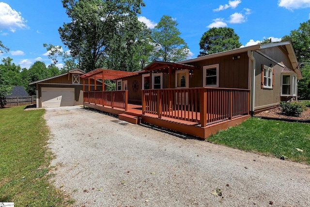 ranch-style house featuring a wooden deck, driveway, an attached garage, and an outbuilding