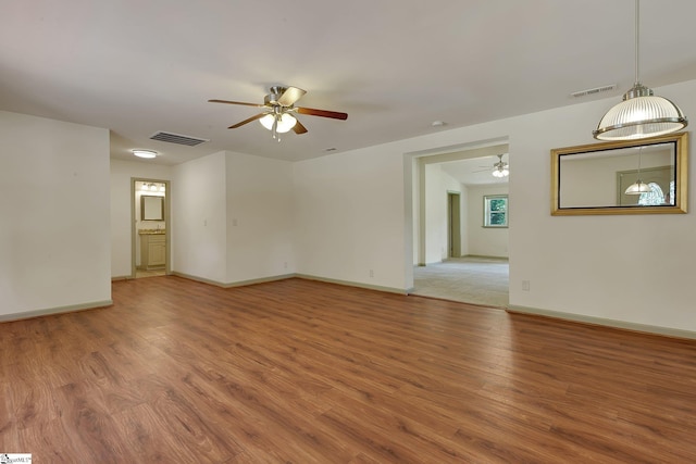 spare room with a ceiling fan, light wood-type flooring, and baseboards