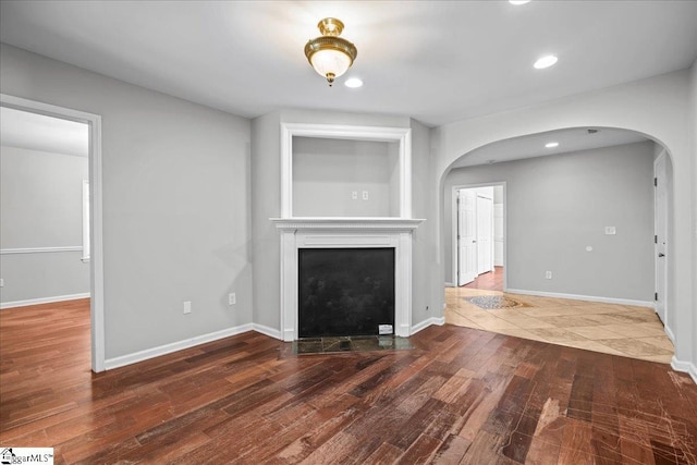 215 Rebecca St, Greenville, SC 29607 - unfurnished living room featuring arched walkways, wood finished floors, a fireplace with flush hearth, recessed lighting, and baseboards