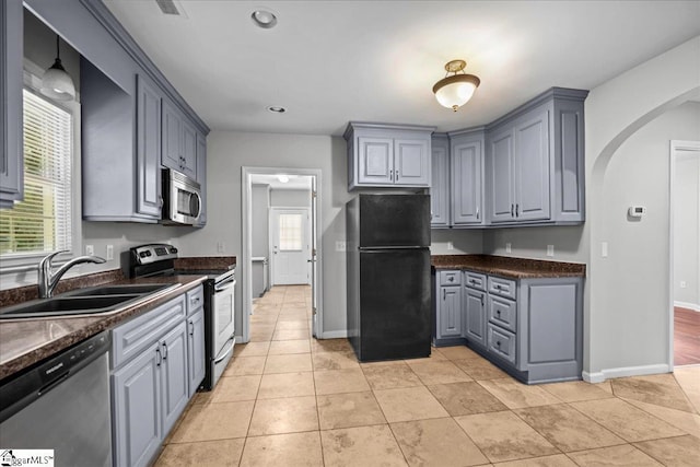 215 Rebecca St, Greenville, SC 29607 - kitchen featuring appliances with stainless steel finishes, a sink, gray cabinetry, dark countertops, and arched walkways