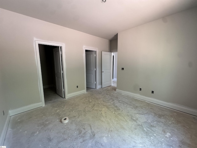 unfurnished bedroom with a spacious closet, baseboards, and concrete floors
