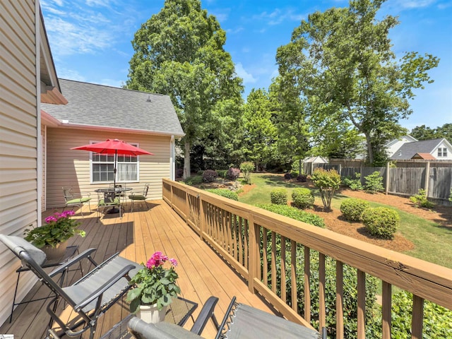 wooden terrace with outdoor dining area and a fenced backyard