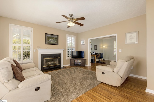 living area featuring ceiling fan, wood finished floors, and baseboards