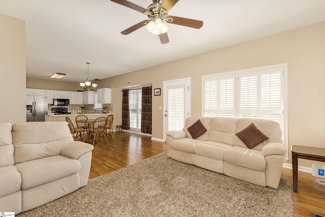 living area with wood finished floors, a chandelier, ceiling fan, and baseboards