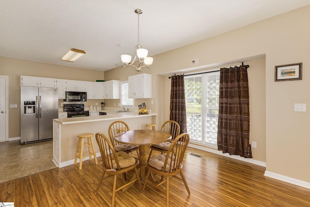 dining room with a chandelier, healthy amount of natural light, wood finished floors, and baseboards