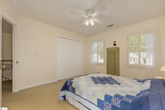 bedroom with light carpet, a ceiling fan, a closet, and baseboards