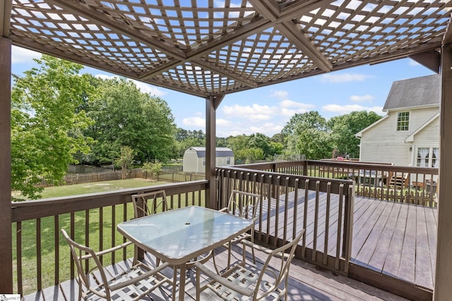 wooden terrace with a storage unit, outdoor dining space, an outdoor structure, a pergola, and view of scattered trees