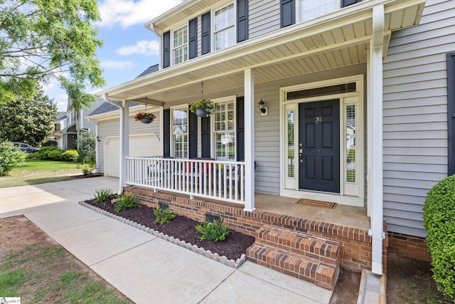 entrance to property with covered porch, driveway, and a garage