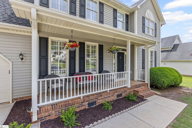 view of exterior entry featuring covered porch and a garage