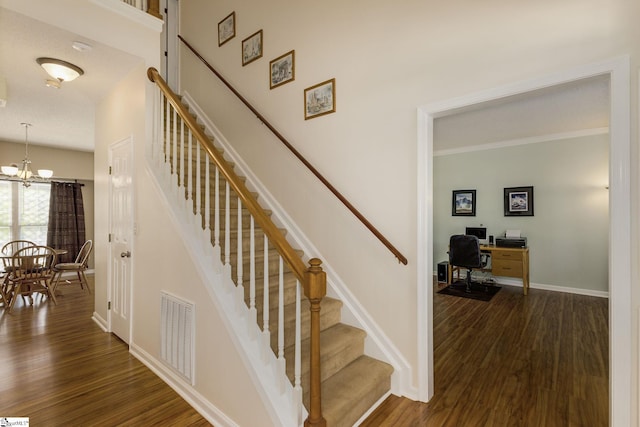 stairs with wood finished floors, a chandelier, and baseboards