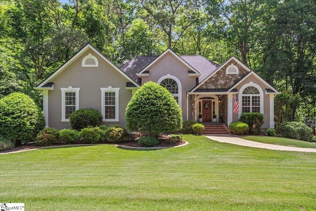 view of front of house with stucco siding, stone siding, a front lawn, and view of scattered trees