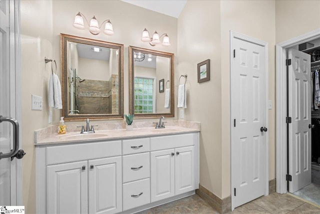 full bath with double vanity, a shower, and baseboards