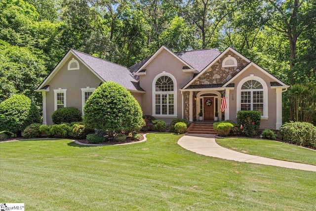 ranch-style home featuring stucco siding, a front lawn, and stone siding