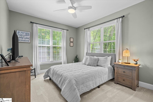 bedroom featuring light carpet, baseboards, and a ceiling fan