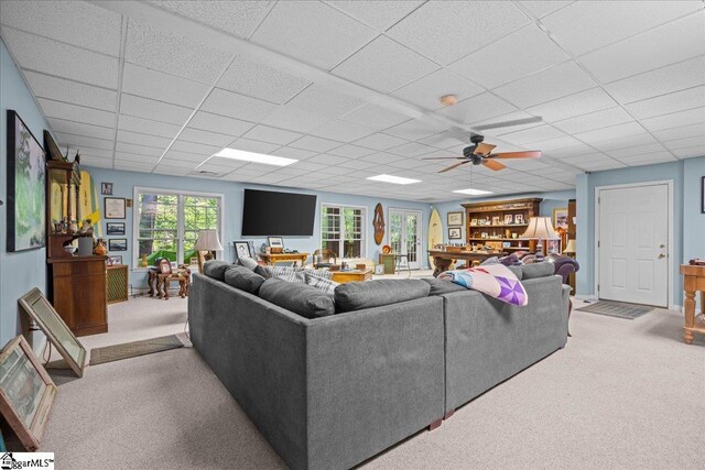 living room with carpet flooring, a drop ceiling, and a ceiling fan