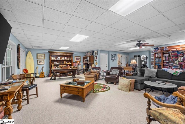 living room with carpet, a drop ceiling, and ceiling fan