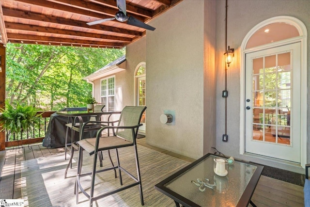 wooden terrace with a ceiling fan and outdoor dining area