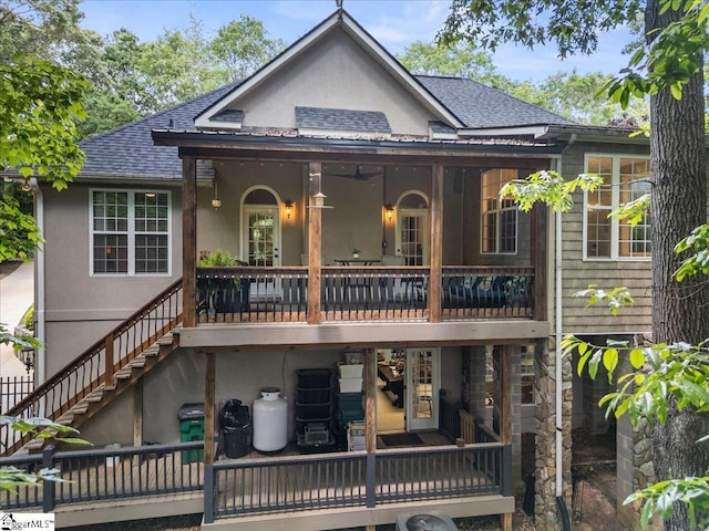 rear view of house with a shingled roof, stucco siding, and stairway