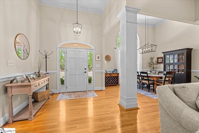 entryway with a chandelier, plenty of natural light, ornate columns, ornamental molding, and a high ceiling
