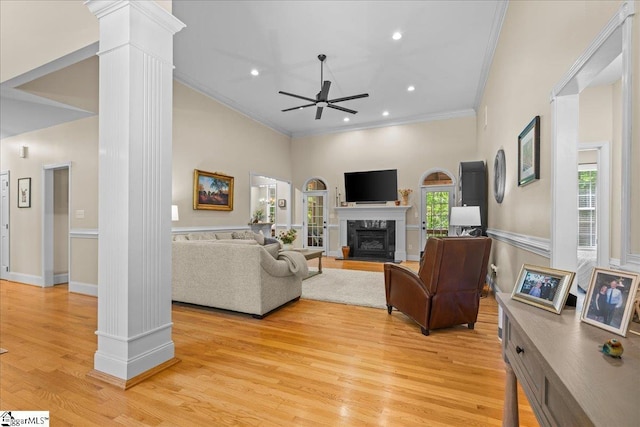 living room with ornate columns, ceiling fan, crown molding, a premium fireplace, and light wood-type flooring