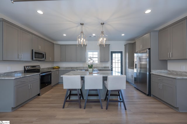 kitchen featuring appliances with stainless steel finishes, gray cabinets, a breakfast bar area, and recessed lighting