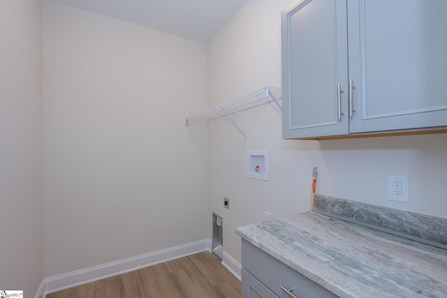 laundry area featuring hookup for a washing machine, light wood-type flooring, hookup for an electric dryer, cabinet space, and baseboards