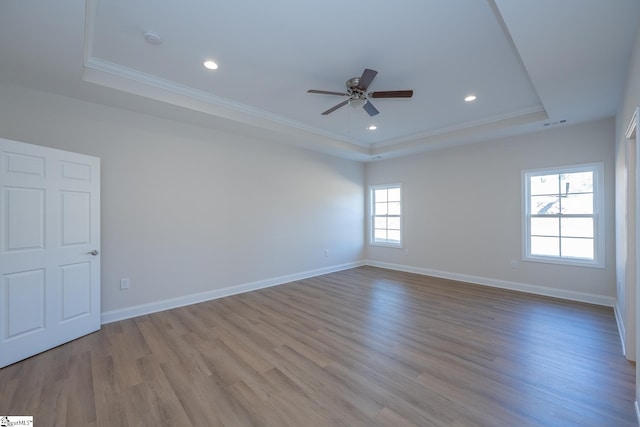 unfurnished room featuring a raised ceiling, ornamental molding, ceiling fan, wood finished floors, and recessed lighting