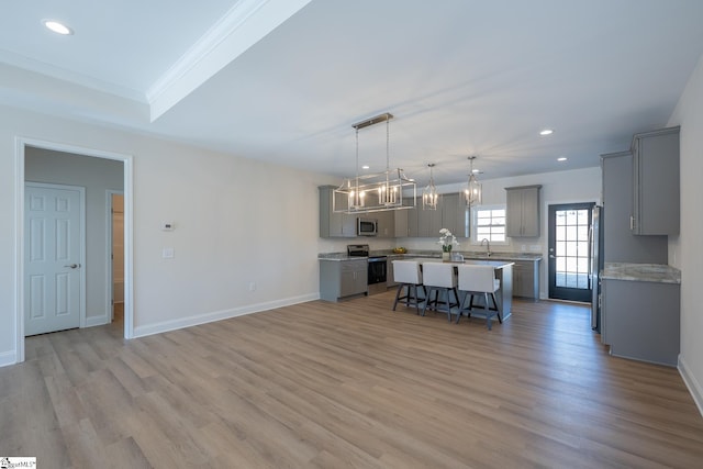 kitchen with gray cabinetry, stainless steel appliances, a kitchen breakfast bar, a chandelier, and a center island