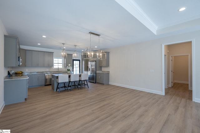 kitchen with gray cabinets, stainless steel appliances, a kitchen breakfast bar, recessed lighting, and a kitchen island
