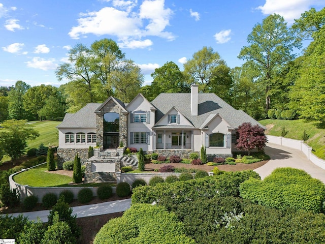 view of front of home featuring stone siding, a chimney, and stucco siding