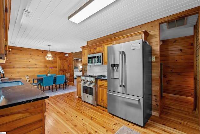 295 Sugarhill Rd, Seneca, SC 29672 - kitchen featuring appliances with stainless steel finishes, dark countertops, wood walls, light wood-type flooring, and decorative light fixtures