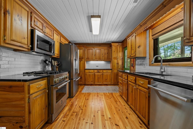 295 Sugarhill Rd, Seneca, SC 29672 - kitchen featuring appliances with stainless steel finishes, a sink, brown cabinetry, dark countertops, and light wood-type flooring