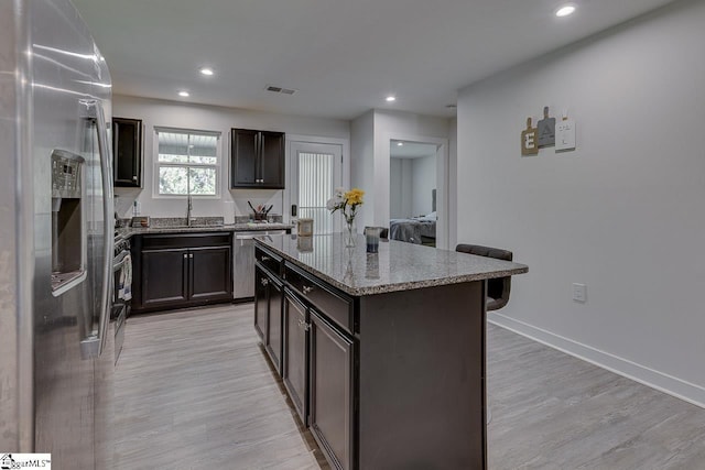 321 Aldworth Ln, Fountain Inn, SC 29644 - kitchen featuring stainless steel appliances, a breakfast bar area, a center island, stone counters, and light wood-type flooring