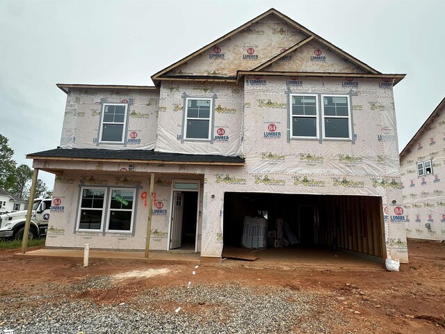 unfinished property with a garage, covered porch, and dirt driveway