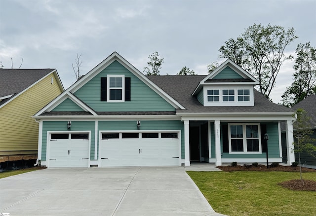 craftsman-style house with concrete driveway, a front yard, and a shingled roof