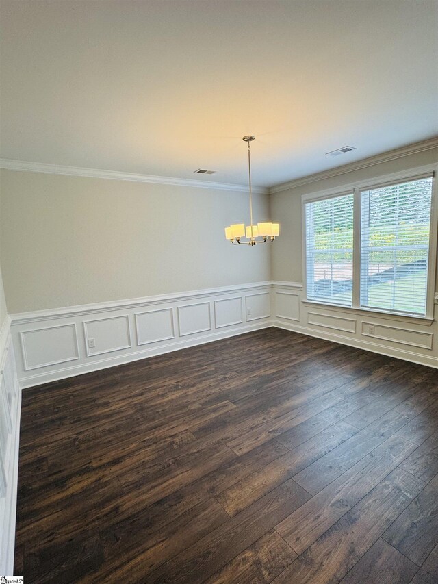 unfurnished dining area featuring a chandelier, ornamental molding, dark wood-type flooring, a wainscoted wall, and a decorative wall