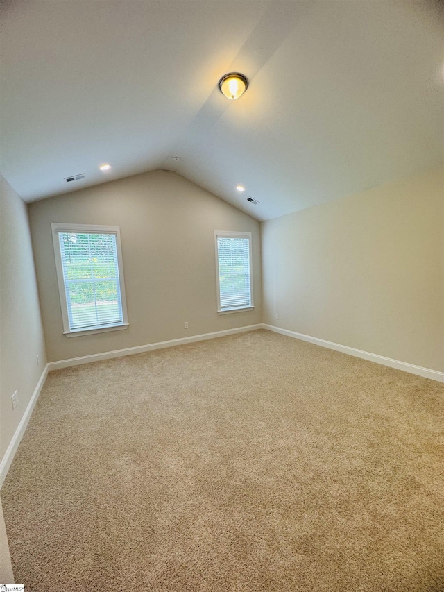 carpeted spare room with lofted ceiling and baseboards