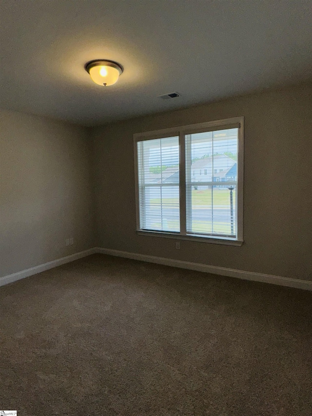 carpeted empty room featuring baseboards