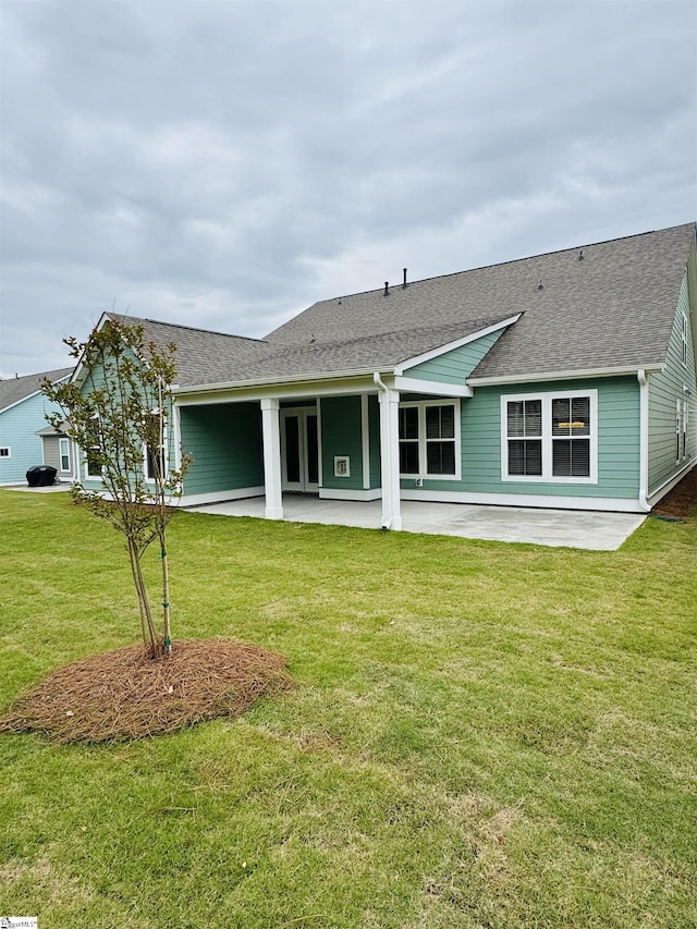 back of house with a patio area, a shingled roof, and a yard
