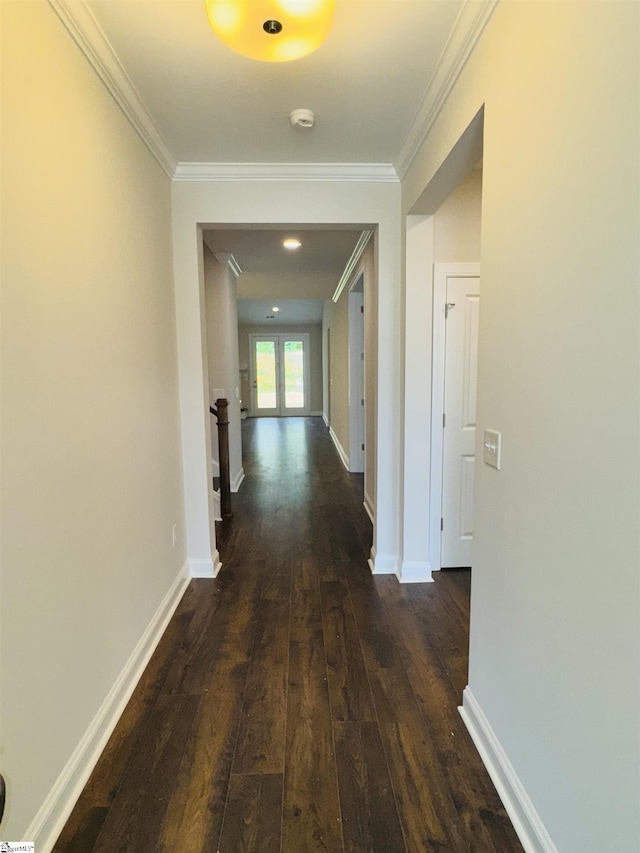 hallway with dark wood finished floors, ornamental molding, and baseboards