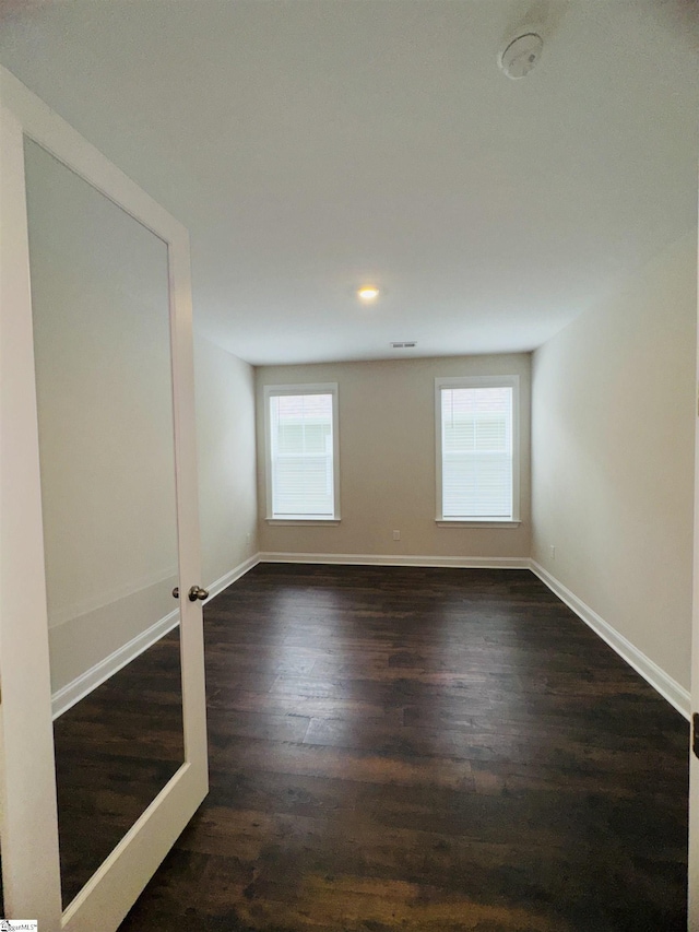 empty room featuring dark wood-type flooring, healthy amount of natural light, baseboards, and recessed lighting