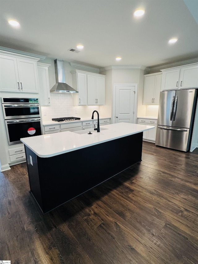 kitchen with stainless steel appliances, wall chimney range hood, a sink, an island with sink, and light countertops