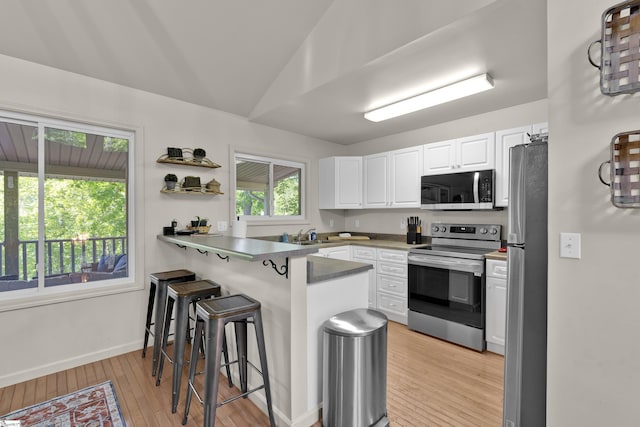 451 Cedar Creek Rd, Sunset, SC 29685 - kitchen with appliances with stainless steel finishes, a peninsula, a kitchen breakfast bar, light wood finished floors, and white cabinets